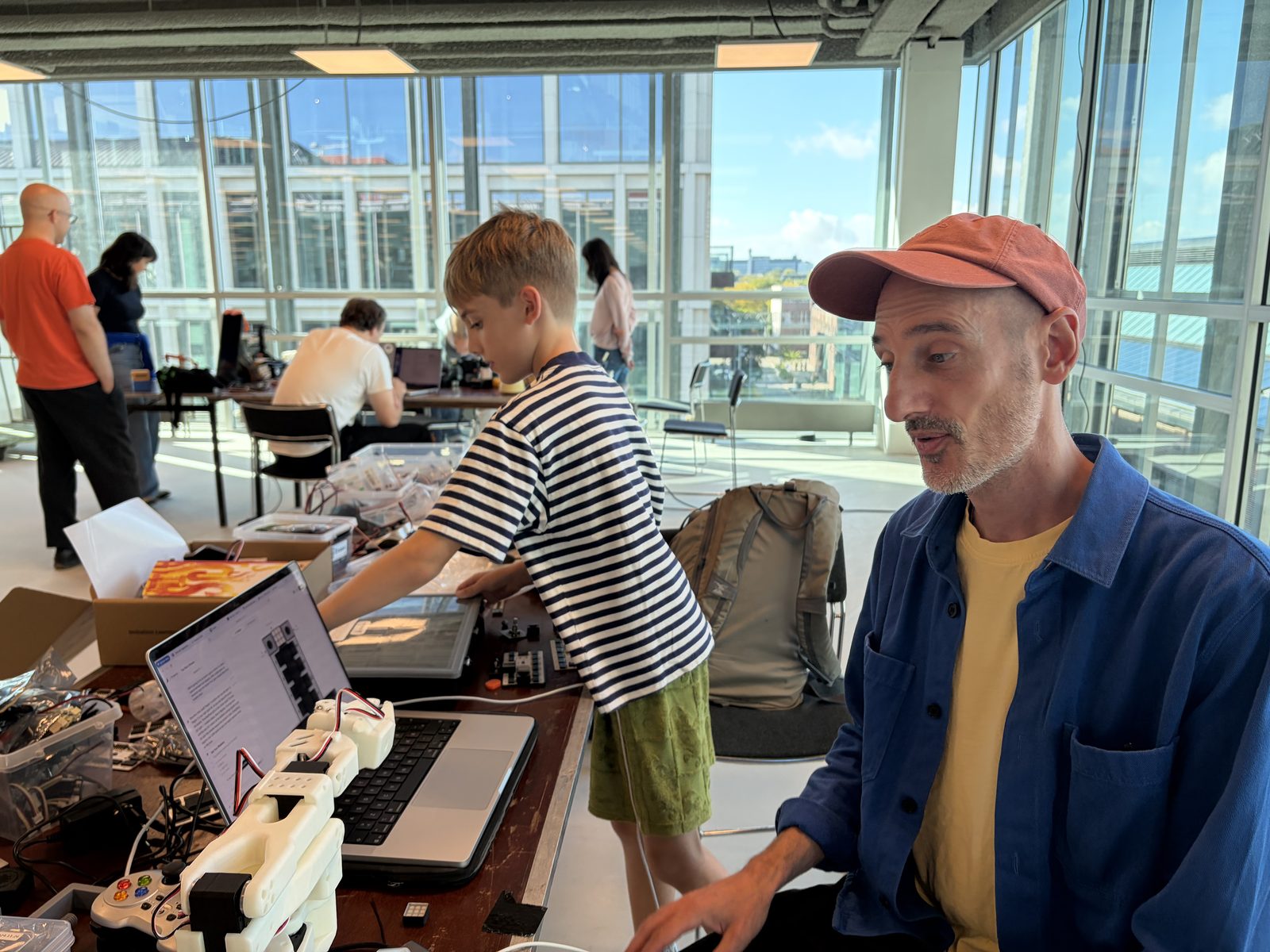 A boy and his dad at the laptop with the robot arm, building the reaction duel