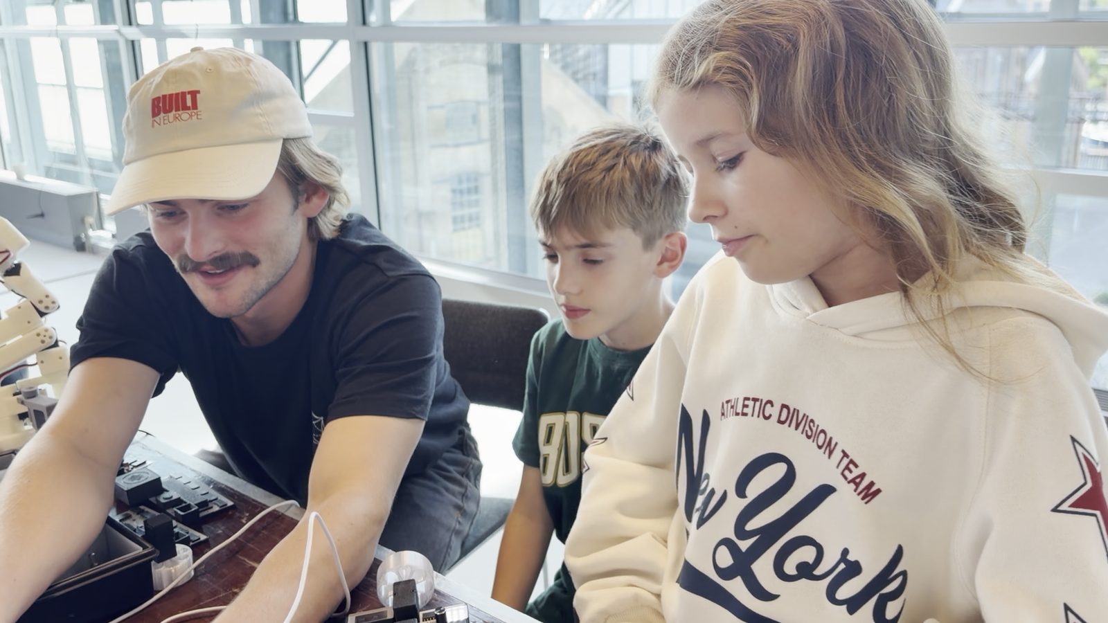 Gustav with a boy and a girl at the table, kit boxes open in front of them