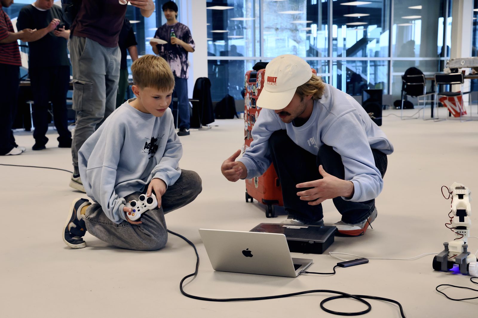 The boy holding the gamepad while Gustav explains with his hands