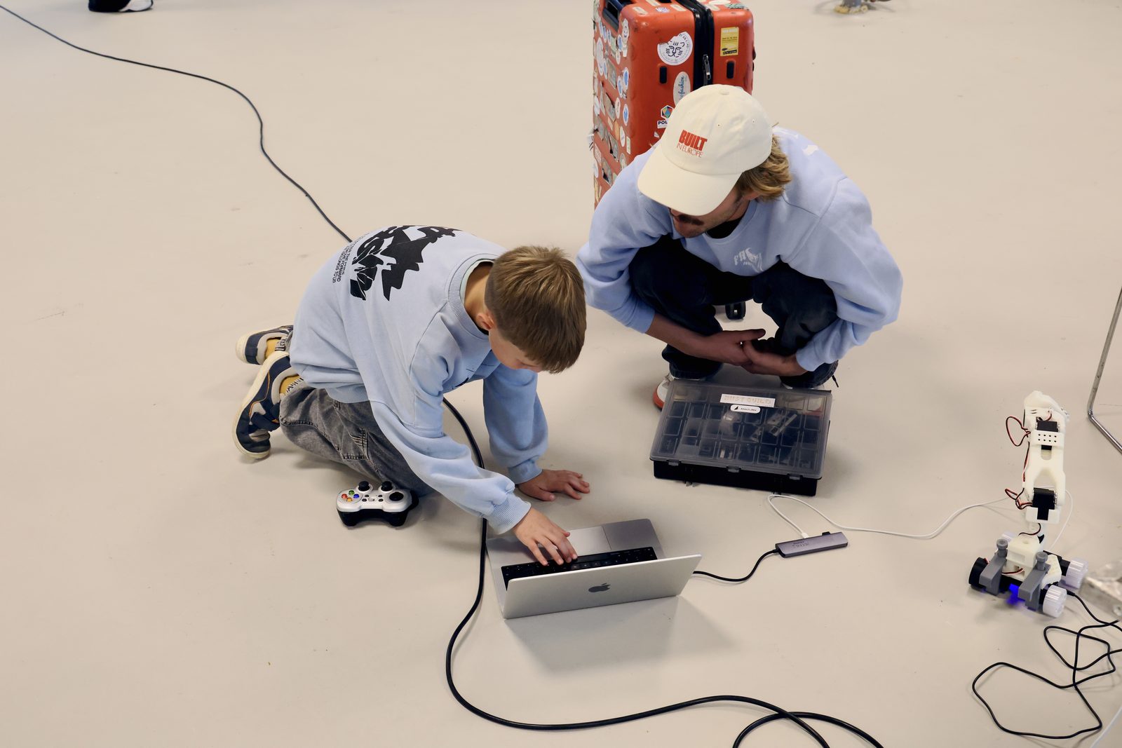The boy leaning in over the laptop, Gustav beside him, the robot car waiting on the floor