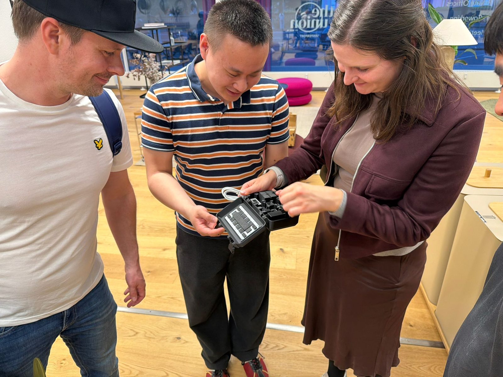 Three people inspecting a handheld device built from modules