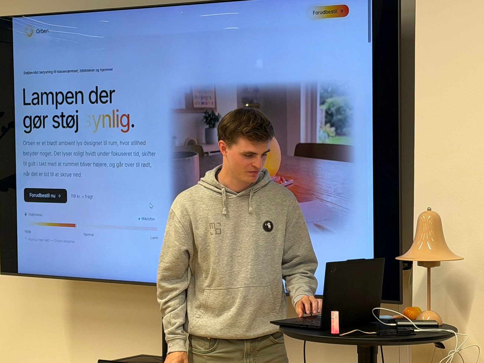 A builder pitching a lamp that makes noise visible, the landing page on the screen behind him