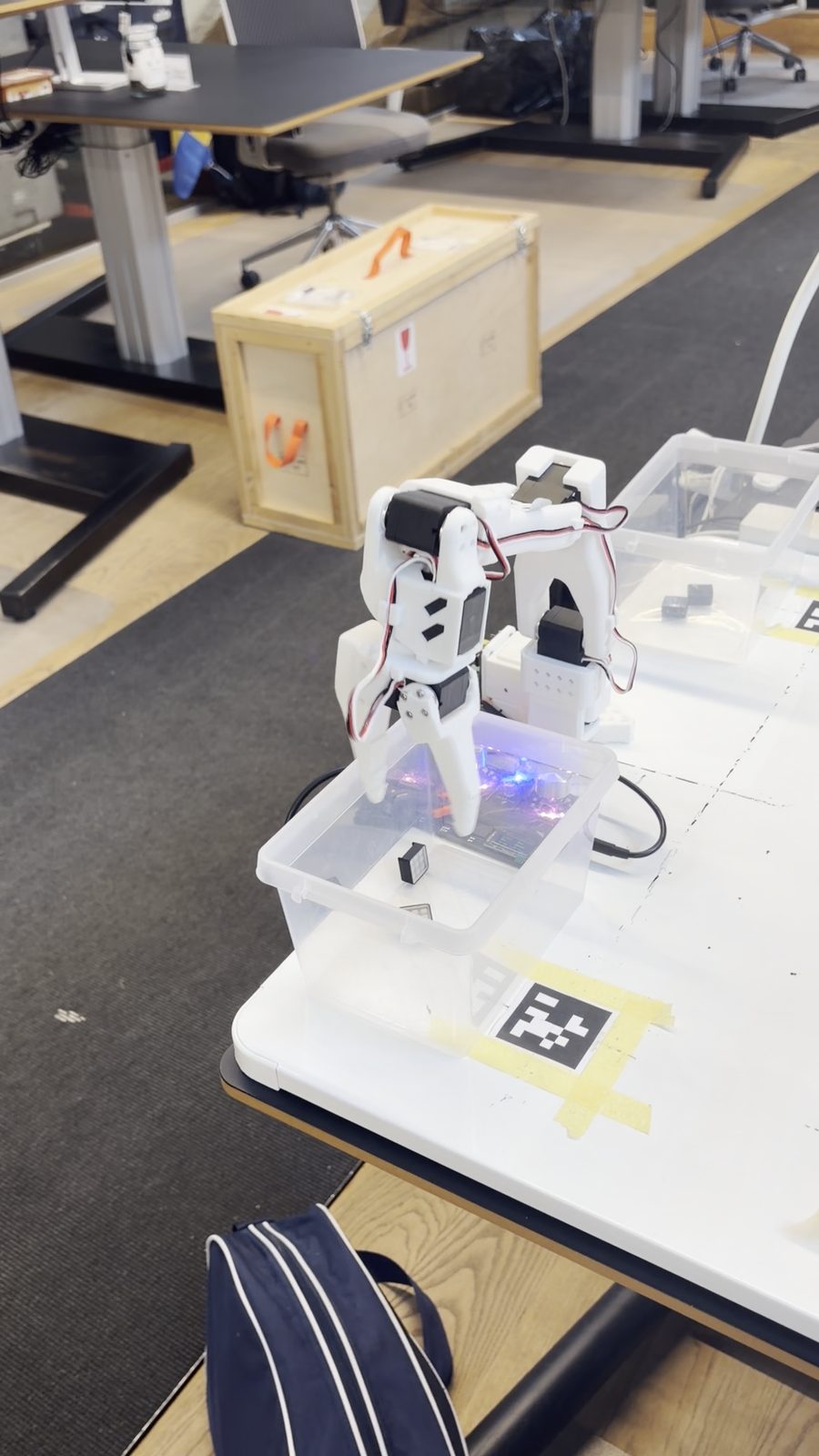 A white robot arm on a table with markers for the camera