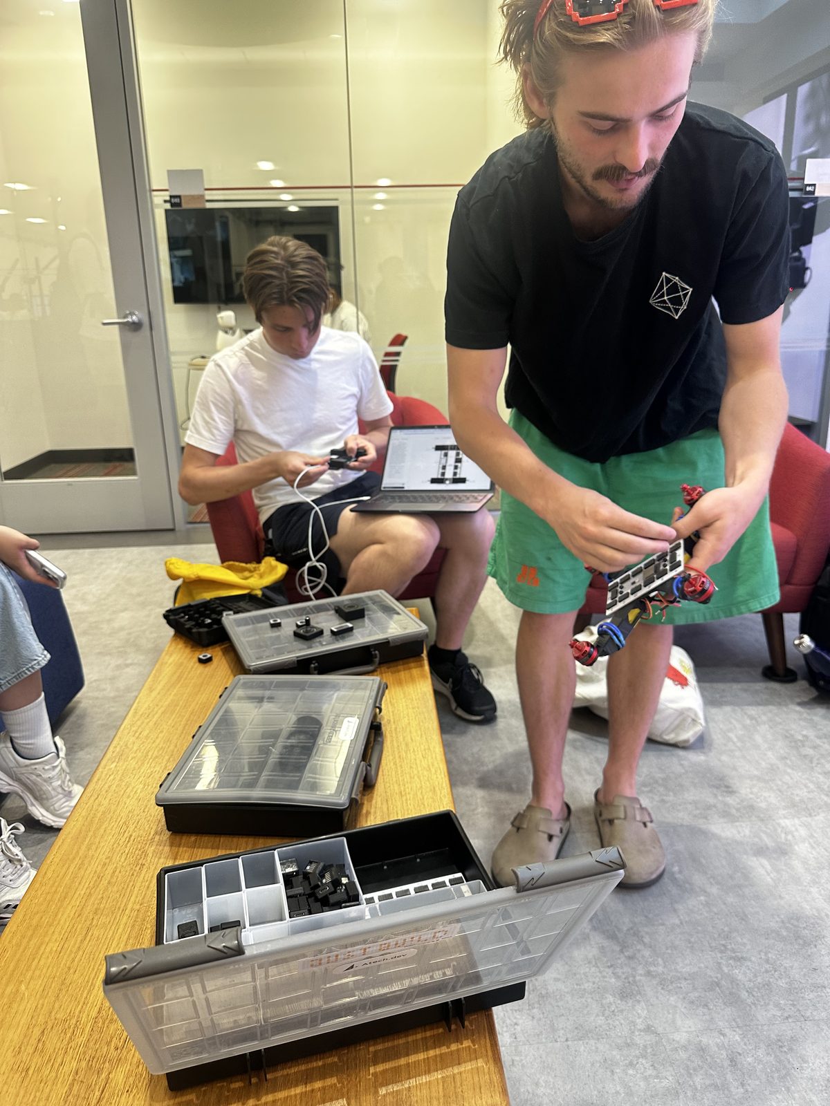 Gustav with an open kit case, students building around him