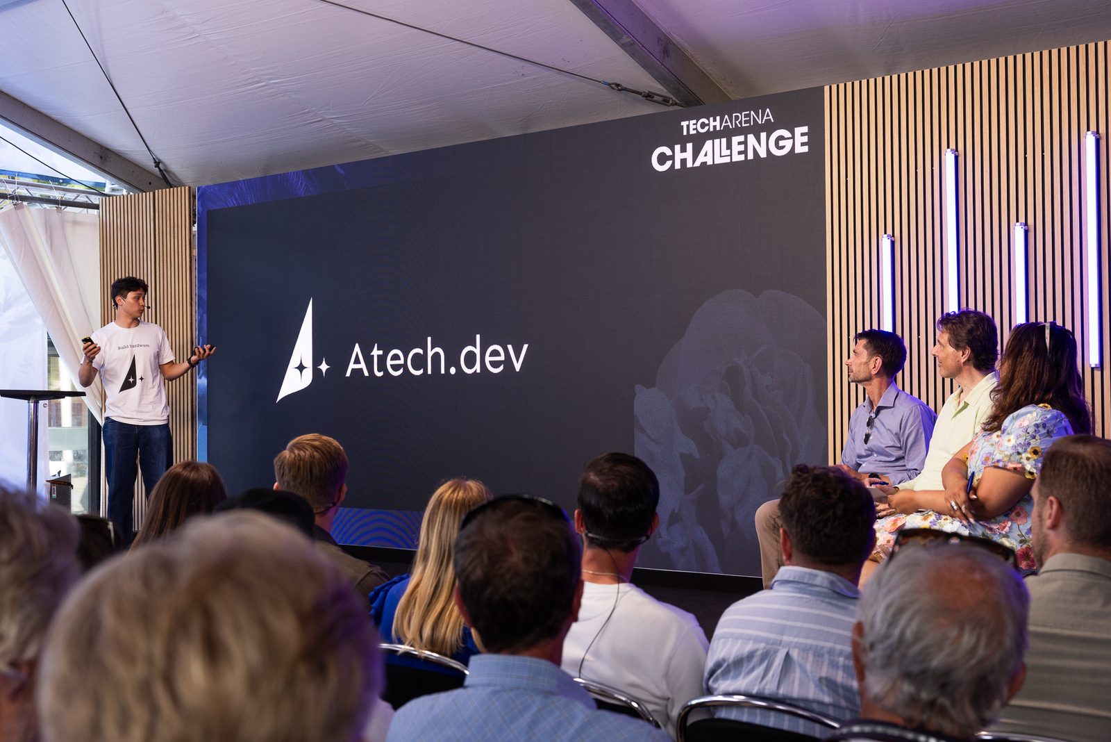 Pitching on the Techarena Challenge arena stage, Atech.dev on the screen