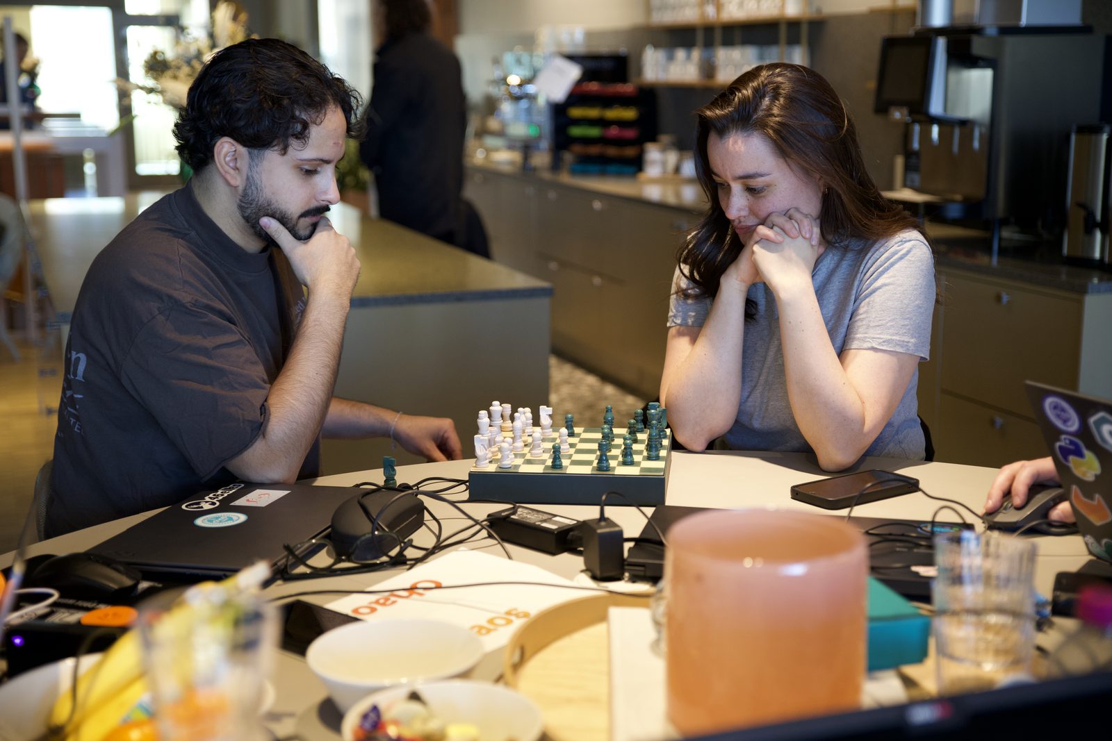 Two builders playing chess between laptops and modules